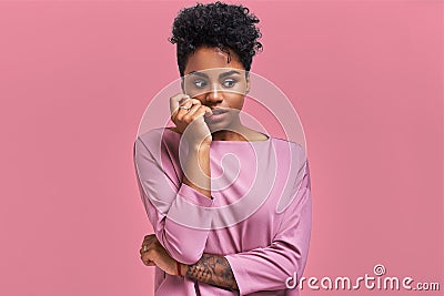 Embarrassed African American woman pursed lips, looks with puzzlement, hears something not clear, dressed in casual top Stock Photo