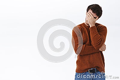 Embarrassed and bothered young man fed up, tired of having this useless conversation, make facepalm gesture and standing Stock Photo