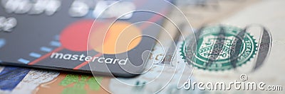 Embossed chipped mastercard credit card and hundred dollar bank notes closeup Editorial Stock Photo