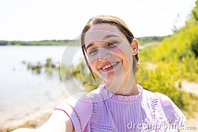 Lakeside Selfie Joy: Radiant Girl in Nature Stock Photo