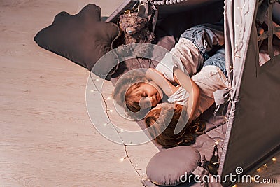 Embracing each other and sleeping. Laying down together. Two little girls is in the tent in domestic room Stock Photo