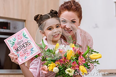 embracing mother and daughter with mothers day greeting card Stock Photo