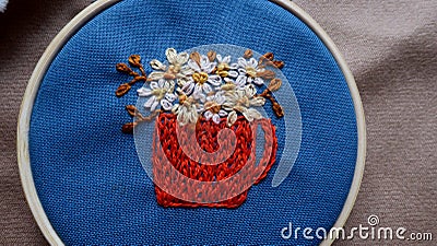 Embroidered cup with chamomile flowers in a hoop Stock Photo