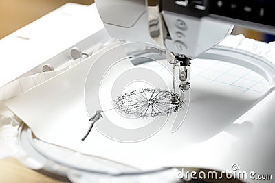 embroidery with embroidery machine - dandilon on white leatherette - view on embroidery process Stock Photo