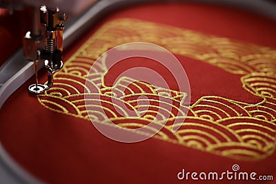 Embroidery of traditional shell pattern framing pig outline with gold on red fabric by modern embroidery machine Stock Photo