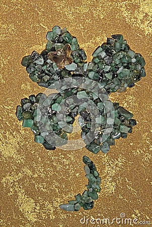 Emerald crystals four leaf clover shape on gold luxury painted background Stock Photo