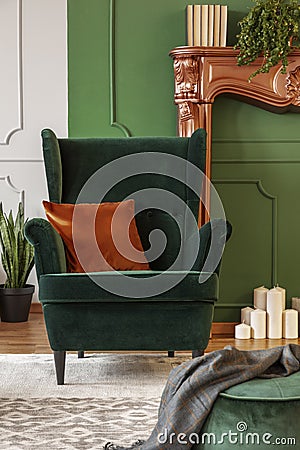 Green wing back chair with orange pillow in luxury living room interior Stock Photo