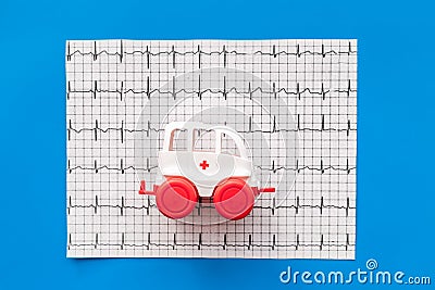 Emergency care concept. Ambulance vehicle toy near cardiogram on blue background top view Editorial Stock Photo
