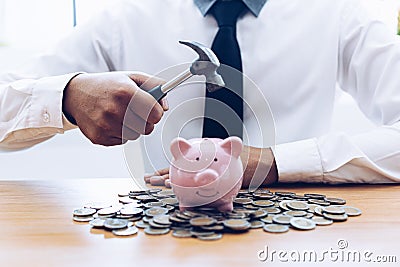 Emergency finance, Businessman using a hammer is about to destroy the pink piggy bank Stock Photo