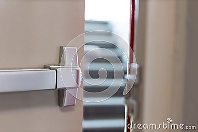 Emergency fire exit door. Closed up latch and rusty door handle of emergency exit. Push bar and rail for panic exit. Open one way Stock Photo