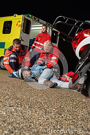 Emergency team helping injured motorbike driver Stock Photo