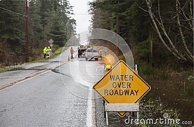 Emergency workers road crew placing warning signs on flooded highway. Hazards after a rain storm. Stock Photo