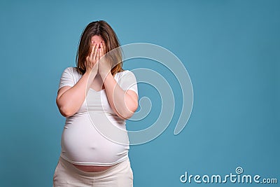Emotion of crying pregnant woman, studio shot on blue background Stock Photo