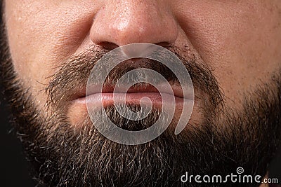 emotion of disgust, hatred close-up on face and lips of young unrecognizable man with black beard and mustache, concept Stock Photo