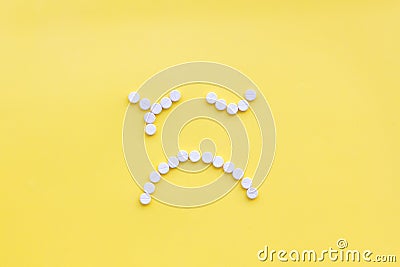 Emotion management concept. Overcome depression. Sad face lined with pills. Yellow background top view copy space Stock Photo