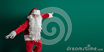 Emotional actor in costume of Santa Claus with long beard gestures and poses on green background Stock Photo