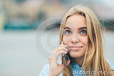 Emotional beautiful blonde talking on the phone outdoors. Female Corrupt faces and indulges in chatting with friends on Stock Photo