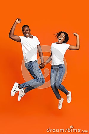Emotional black couple holding hands and jumping up Stock Photo