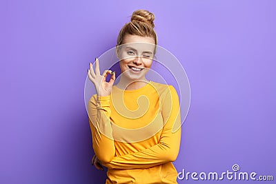 Emotional charming woman showing ok sign with fingers and winking Stock Photo