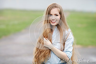 Emotional close up portrait of a adult pretty blonde woman with gorgeous extra long hair posing outdoors against blurred park back Stock Photo