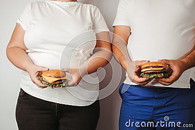 Overweight couple snacking with hamburgers Stock Photo