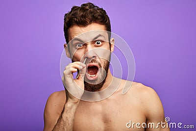 Emotional funny man pucking nose hair with tweezers Stock Photo