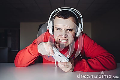 Emotional gamer plays home games on the joystick. The young man plays computer games using a gamepad. Stock Photo