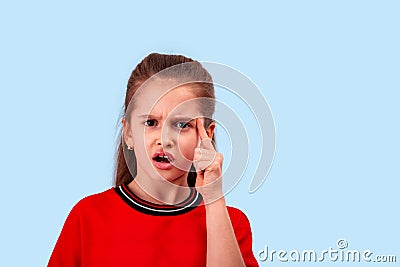 Emotional little girl exclaims from outrage or discontent holding her index finger at the temple Stock Photo