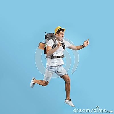 Emotional male tourist with backpack and camera jumping on turquoise background Stock Photo