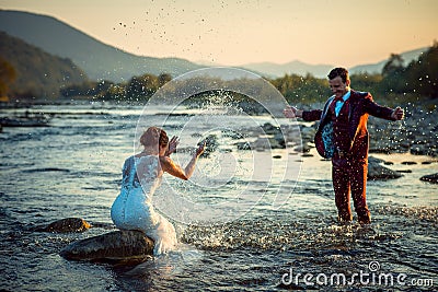 Emotional Outdoor Wedding Portrait Happy Beautiful Smiling Newlywed Couple Playing Splashing Water Having Fun Sunset Stock Photo