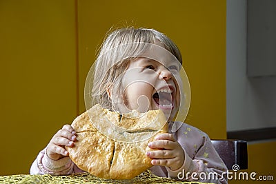 Emotional portrait of a little girl eating a large bread cake with spinach and cheese on a neutral background. Concept: a snack on Stock Photo