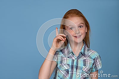 Emotional portrait of a young funny naughty girl with red hair against blue background Stock Photo