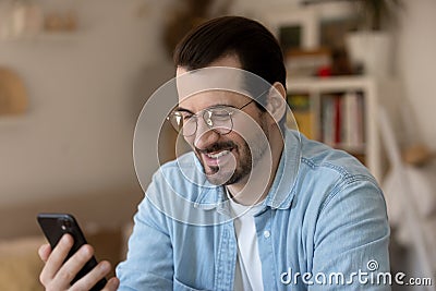 Emotional positive young handsome guy reading message with good news. Stock Photo