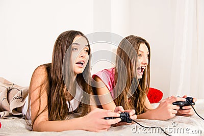 Emotional pretty girl lying in bed and plaing video games Stock Photo