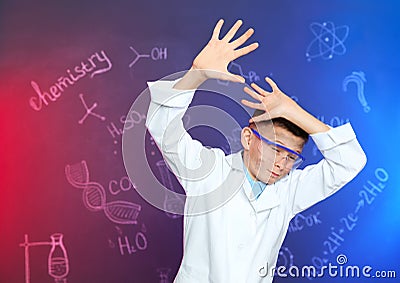 Emotional pupil shielding himself against blackboard with written chemistry formulas Stock Photo