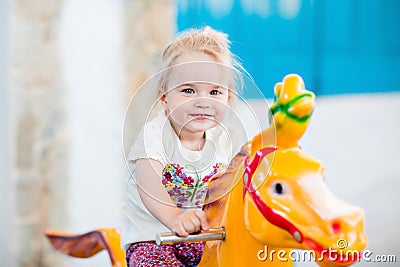 Emotional smiling little girl riding on the carousel Stock Photo