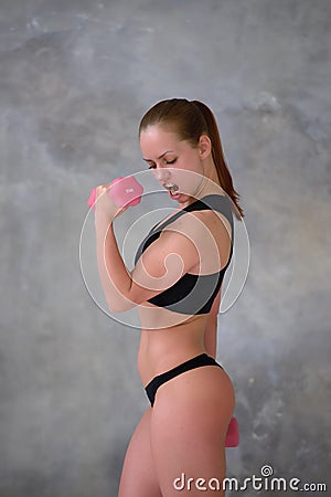 Emotional sports girl shouts, doing exercise with dumbbells Stock Photo