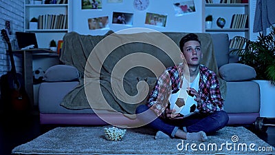 Emotional student watching soccer match on tv, national team winning game Stock Photo