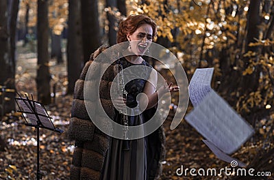 Emotional woman-oboist holding an oboe throwing away the musical sheets Stock Photo