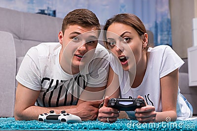 Emotional young couple lying on a rug and playing video games Stock Photo