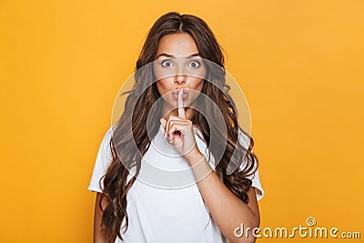 Emotional young pretty woman posing isolated over yellow background showing silence gesture. Stock Photo