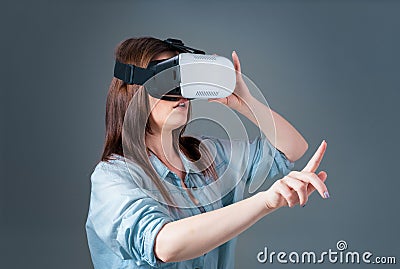 Emotional young woman using a VR headset and experiencing virtual reality on grey background Stock Photo