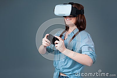 Emotional young woman using a VR headset and experiencing virtual reality on grey background Stock Photo