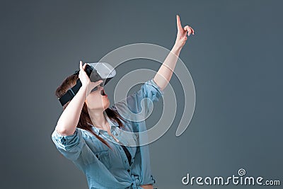 Emotional young woman using a VR headset and experiencing virtual reality on grey background Stock Photo