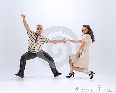 Dynamic portrait of emotional man and woman dancing sport dances isolated on white background. 50s, 60s ,70s american Stock Photo