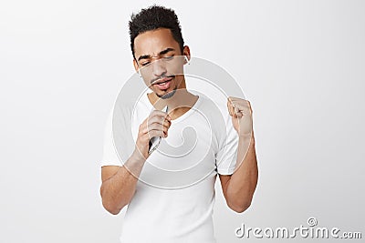 Emotive lyrics hit young musician. Handsome african-american male student in white t-shirt, raising clenched fist Stock Photo