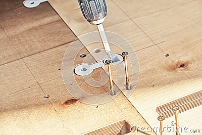 Employee assembles dining table with electric screwdriver outdoors Stock Photo