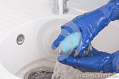 An employee of the cleaning service of residential premises washes a glass glass in water Stock Photo
