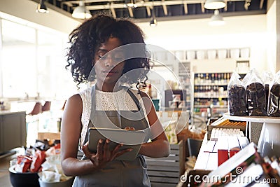 Employee In Delicatessen Checking Stock With Digital Tablet Stock Photo