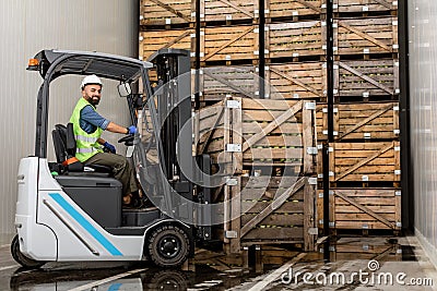 Employee on electric forklift carry container with ripe apples at storage Stock Photo